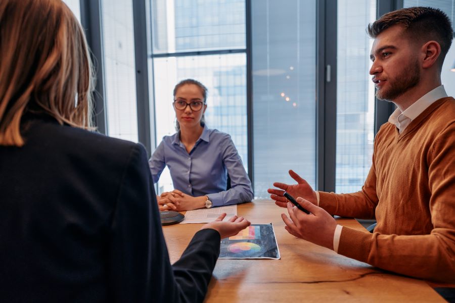 Drei Personen sitzen am Tisch und sprechen über Fehler 