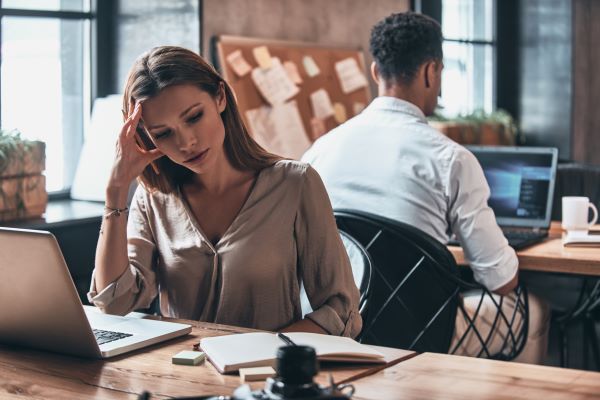 Eine Frau sitzt im Büro und ist überlastet