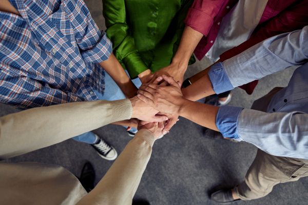 Mit Feedback das Team stärken: Die Hände des Teams werden sich in der Mitte gereicht