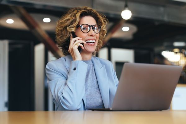 Dekoratives Bild: Frau mit Handy an Laptop