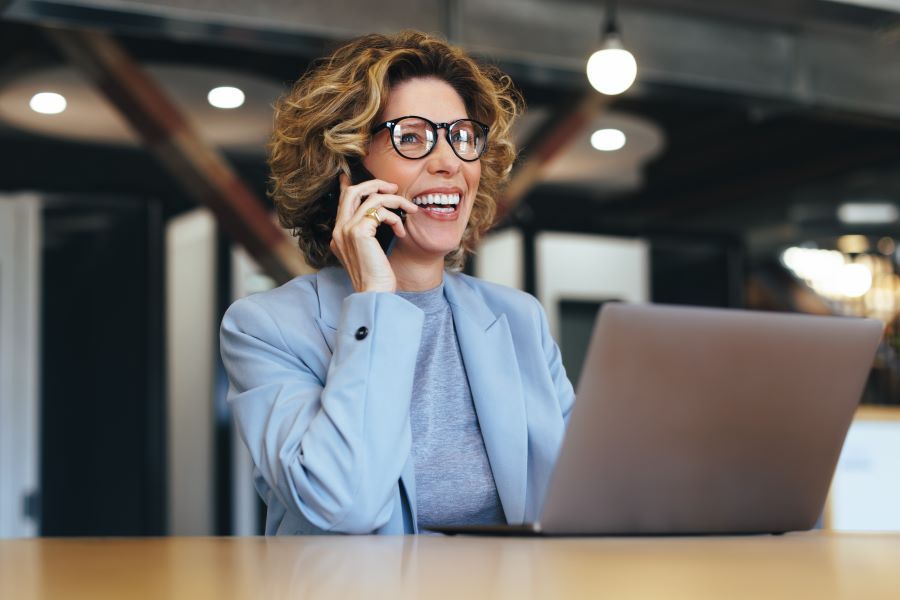 Dekoratives Bild: Frau mit Handy an Laptop