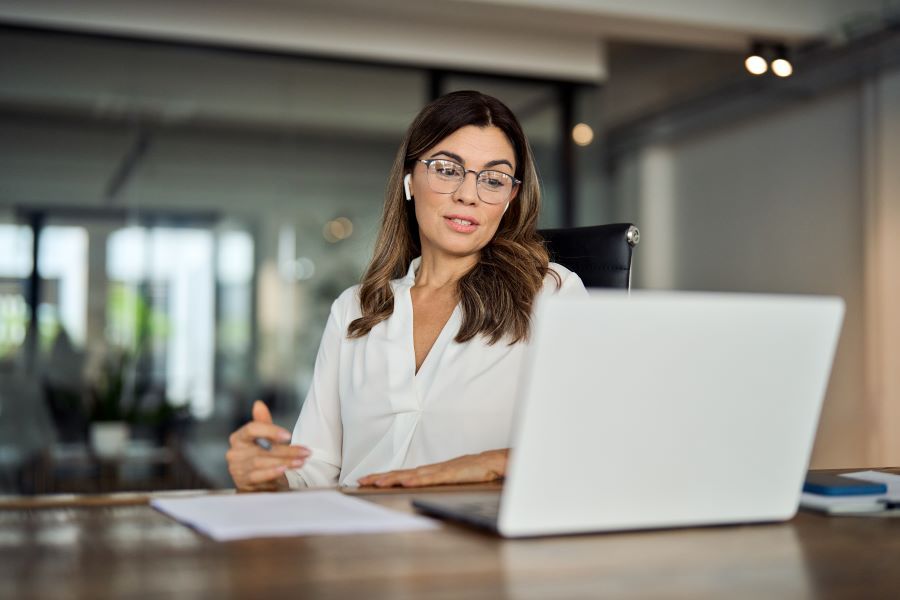 Dekoratives Bild: Frau mit In-Ear-Kopfhörern am Laptop