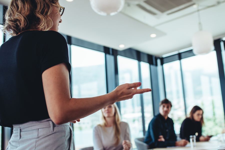 Dekoratives Bild: Frau spricht mit Team an Konferenztisch