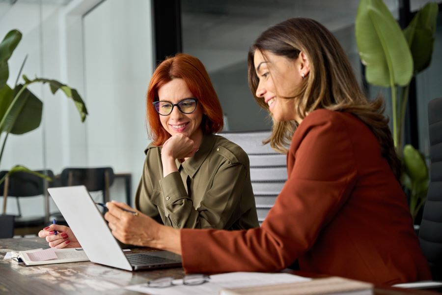 Dekoratives Bild: 2 Frauen mit Laptop und Pflanzen im Hintergrund