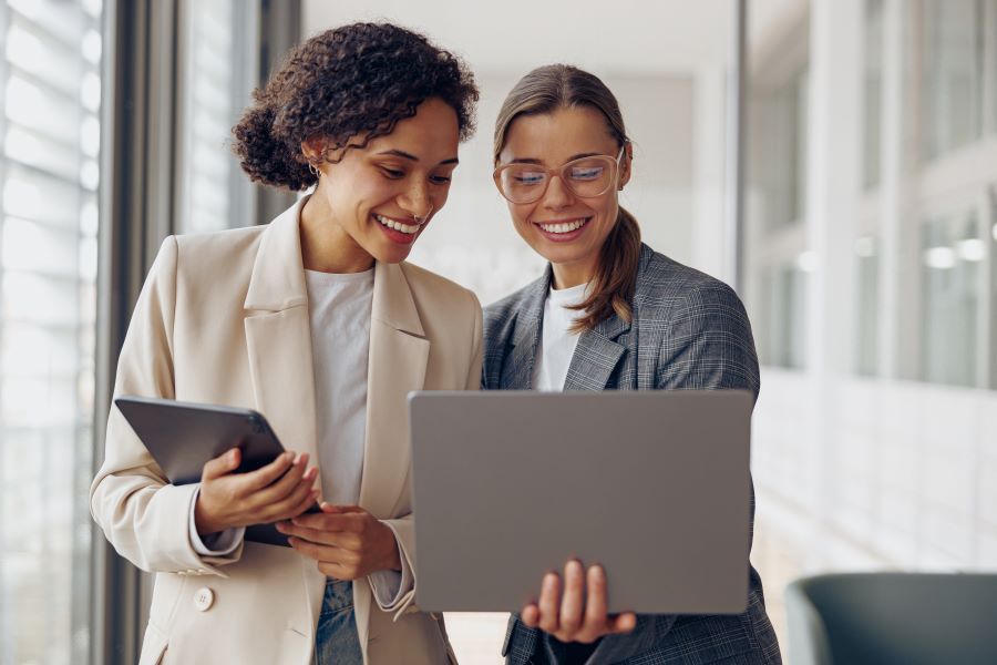 Dekoratives Bild: 2 lächelnde Frauen mit Laptop und Tablet