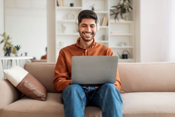 Dekoratives Bild: Mann zuhause mit Laptop und Kopfhörern