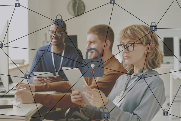 Drei Personen sitzen an einem Schreibtisch und arbeiten, darüber liegt ein Netzwerk aus Schlössern. 